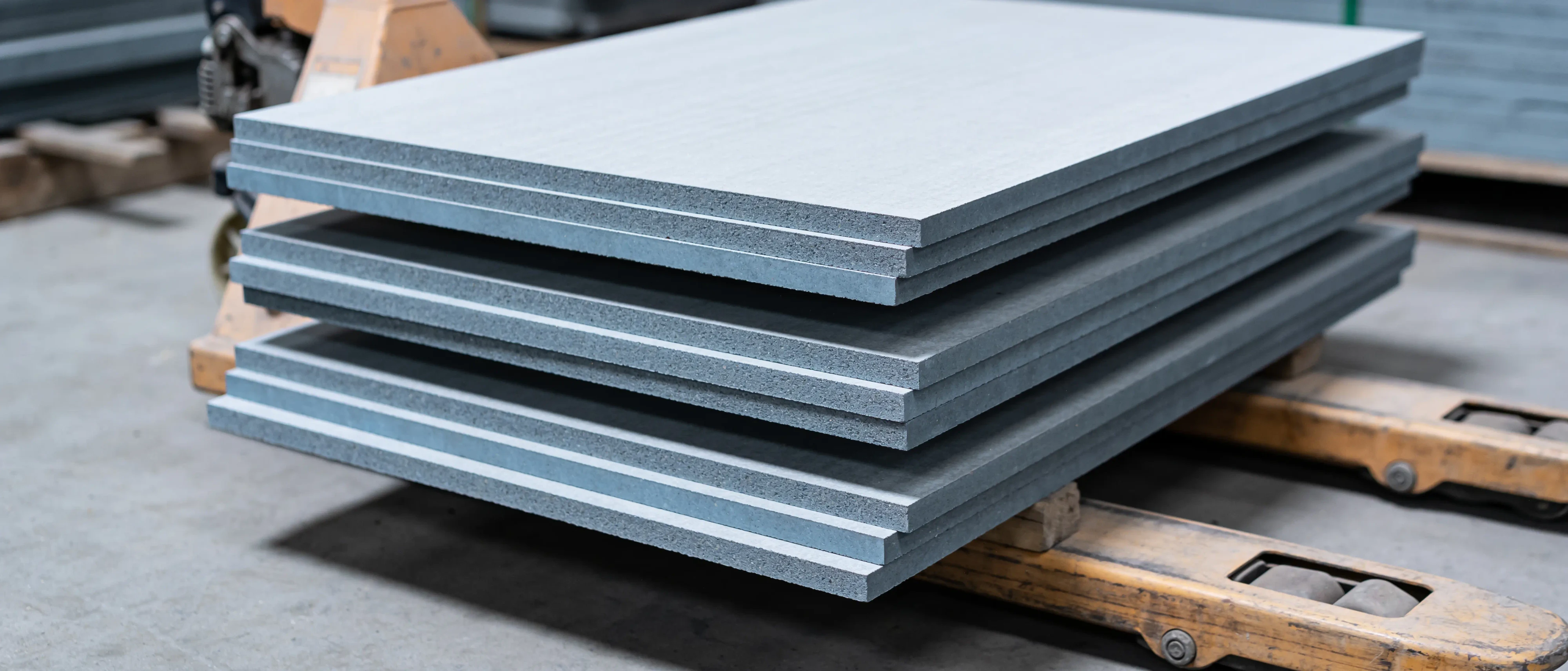 Stapel grauer Faserzementplatten auf einer Palette, Blick auf die Plattenkanten